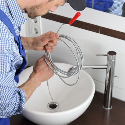 A Plumber Uses a Manual Drain Snake to Unclog a Sink.