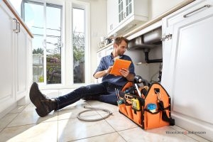 A plumber conducts emergency plumbing repairs on a busted sink.