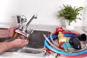 Plumber removes broken faucet to conduct faucet repairs.